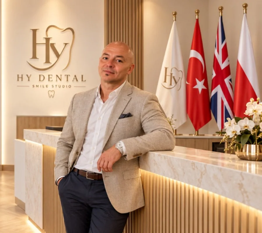 Robert Budzioch am Empfang des HY Dental Smile Studio, mit türkischer, britischer und polnischer Flagge im Hintergrund